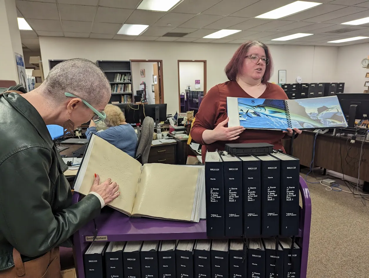 Shannon Crawford-Barniskis touching a map of Westeros in a braille copy of a Game of Thrones Book.